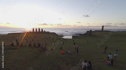 People admiring sunset with Moai in background at Ahu Tahai, Easter Island in Chile. Time-lapse photo