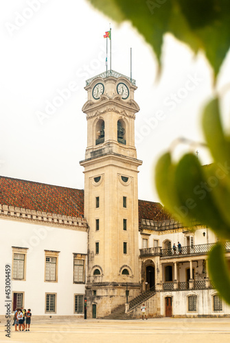 A view at the Tower and Paco das Escolas Square of University of Coimbra through the green tree leaves - Selective focus, Portugal