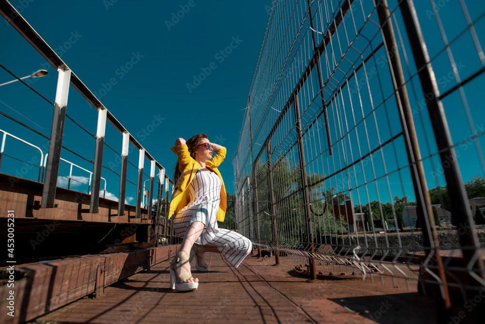 A woman wearing a yellow blouse and glasses enjoying the nice sunny weather while walking. Girl resting outdoors while walking along the river A woman wearing a yellow blouse and glasses enjoying the nice sunny weather while walking. Girl resting outdoors while walking along the river
