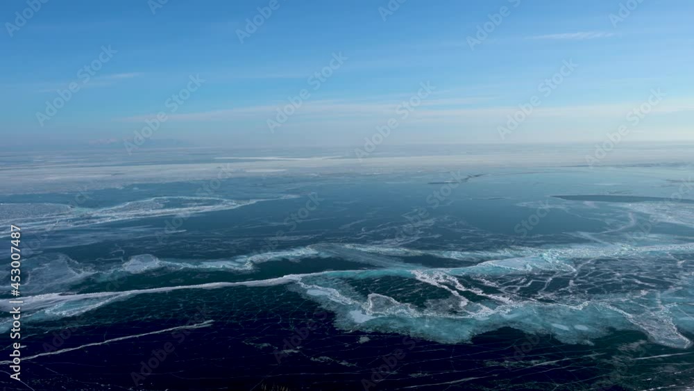 On the surface of the frozen lake, many white cracks. Camera moves horizontally. North line of Olehun Island, Lake Baikal, ice field icicle view. Russia. Jan. 2019 On the surface of the frozen lake, many white cracks. Camera moves horizontally. North line of Olehun Island, Lake Baikal, ice field icicle view. Russia. Jan. 2019