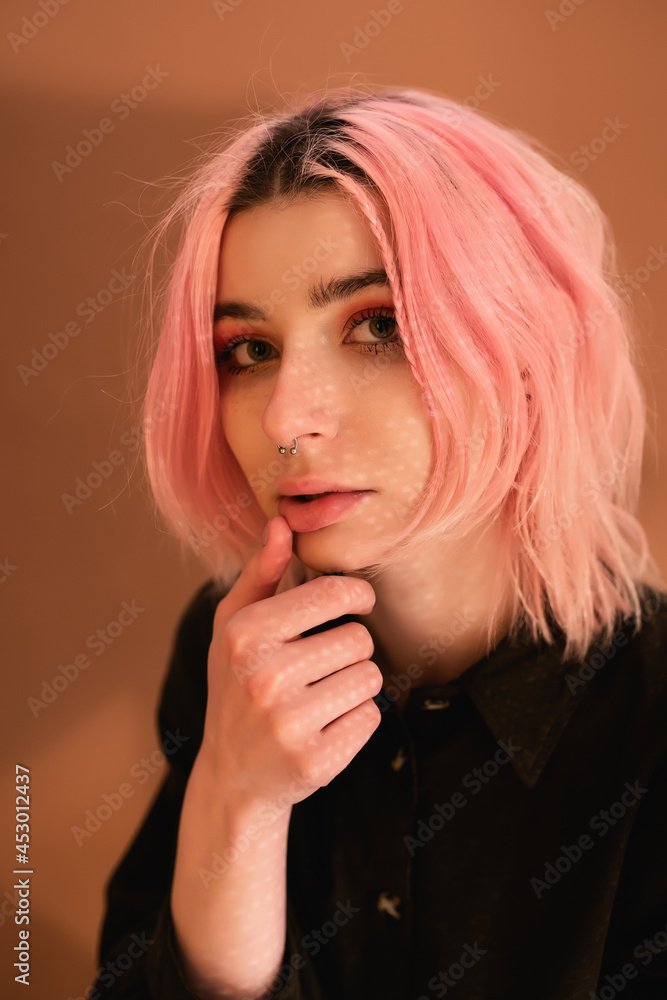 Fototapeta premium Young woman girl with pink hair on orange wall background studio portrait. People sincere emotions lifestyle concept 