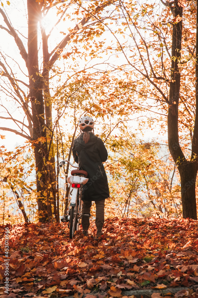 lonely person back to camera with bike in autumn park outdoor environment space and bright sun light vertical photo