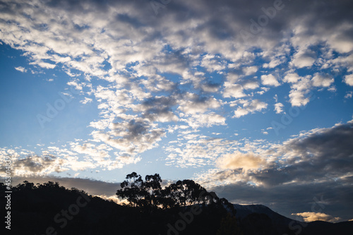 sunset cloud formation creating a V shape across the sky at dusk with eucalyptus gum trees and mountains