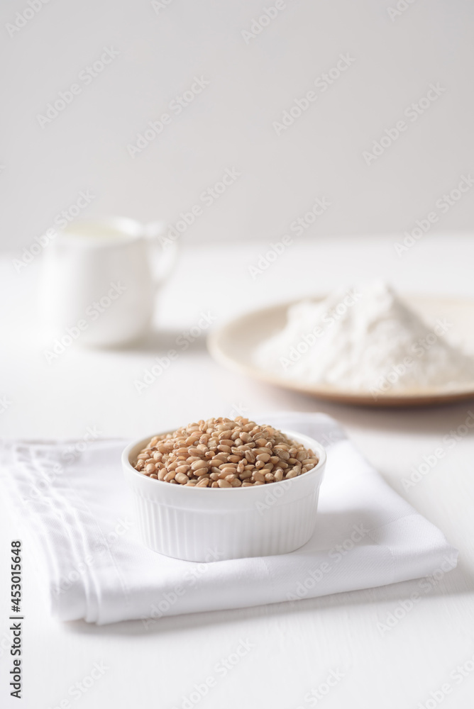 Whole wheat grains and wheat flour on white background. Natural organic products, healthy baking ingredients. Whole wheat grains and wheat flour on white background. Natural organic products, healthy baking ingredients.