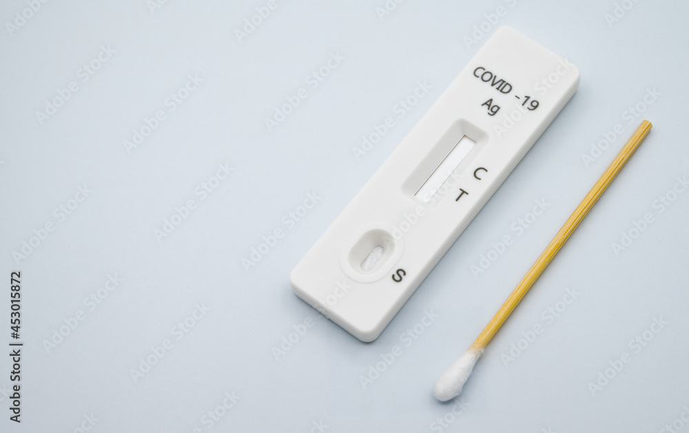 A rapid antigen test pad with short cotton swab on white background. Rapid antigen testing is a screening tool to help detect COVID-19 in people without any symptoms of COVID-19. A rapid antigen test pad with short cotton swab on white background. Rapid antigen testing is a screening tool to help detect COVID-19 in people without any symptoms of COVID-19.