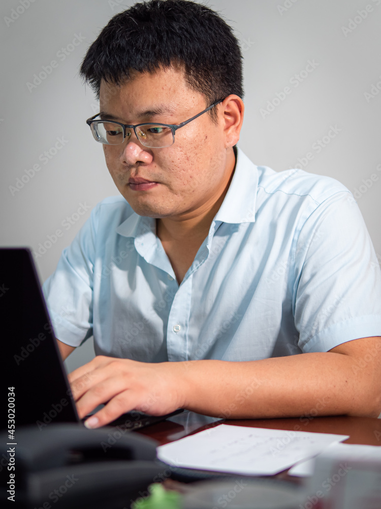 Chinese man sitting in front of office computer Chinese man sitting in front of office computer