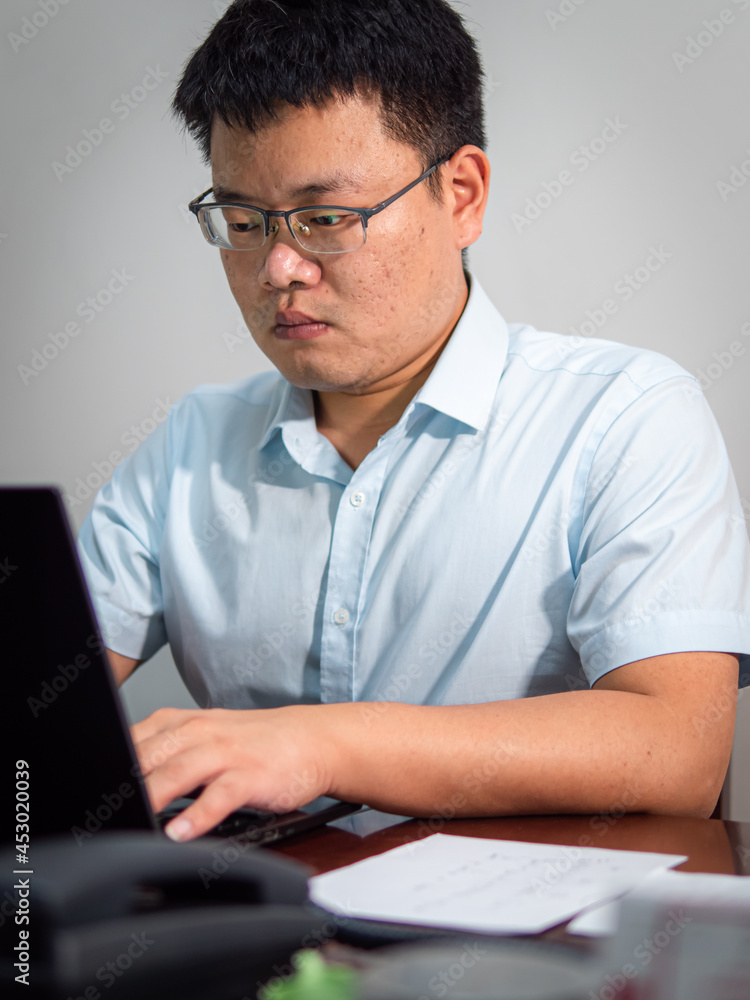 Chinese man sitting in front of office computer Chinese man sitting in front of office computer