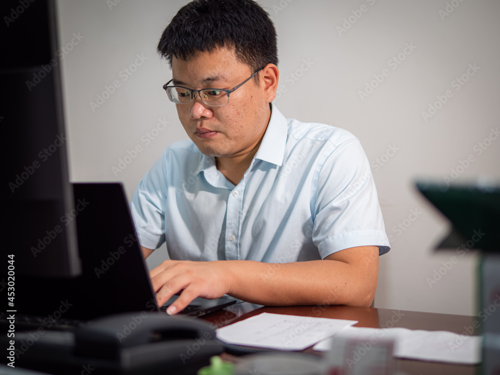 Chinese man sitting in front of office computer Chinese man sitting in front of office computer