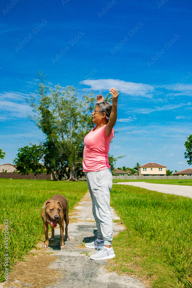 OLD WOMAN DOING EXERCISE IN PARK WITH HER DOG OLD WOMAN DOING EXERCISE IN PARK WITH HER DOG