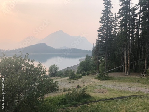 Sky red smoky sunset over Upper Kananaskis Lake in Peter Lougheed Provincial Park, Alberta, Canada. Wildfire season in Canada.  photo