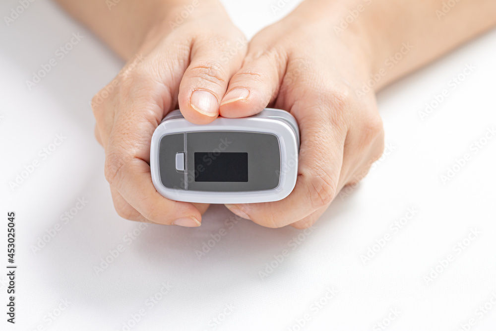 Close-up, Female hands hold the Digital Pulse Oximeter for use with measures the patient's pulse and oxygen saturation (SPO2) on white background. Healthcare concept. Close-up, Female hands hold the Digital Pulse Oximeter for use with measures the patient's pulse and oxygen saturation (SPO2) on white background. Healthcare concept.