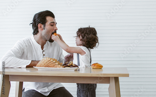 Wallpaper Mural Caucasian handsome father taking care and giving breads and biscuit to his little cute daughter while staying together at home in holidays. Lifestyle, Family and Education Concept. Torontodigital.ca