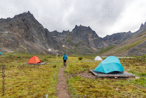Backcountry campground in Tombstone Territorial Park, Yukon during summer time with bright tents and hiker. 