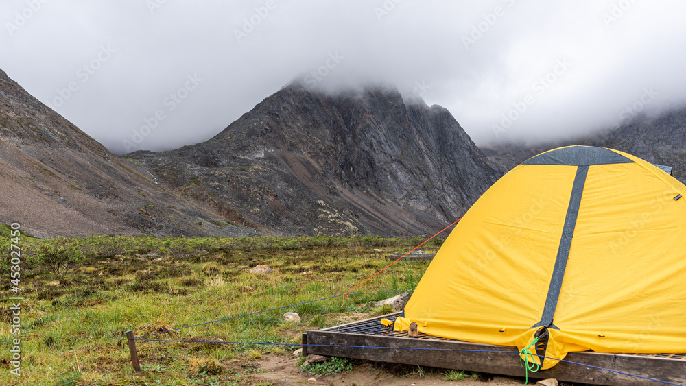 Bright yellow small two person tent in the wilderness of northern Canada on cloudy afternoon. Taken from Grizzly Lake backcountry campground. 