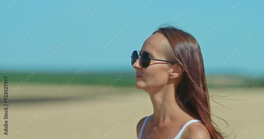 Portrait, a young woman with long hair and sunglasses walking across a field, blue sky. Beautiful rural landscape. Happy life. 4k, ProRes Portrait, a young woman with long hair and sunglasses walking across a field, blue sky. Beautiful rural landscape. Happy life. 4k, ProRes
