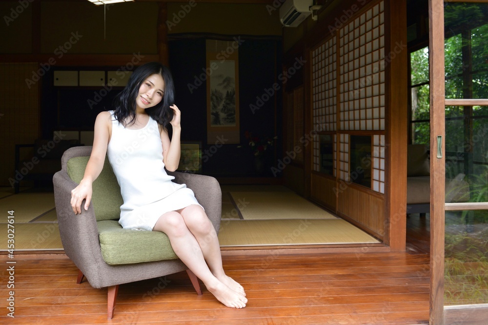 古民家の縁側でソファーに座りくつろぐ白いワンピース姿の若い女性