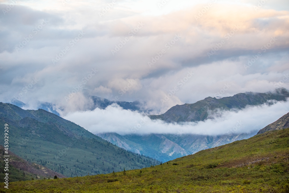 Fototapeta premium Cloudy, misty, foggy landscape of Tombstone Territorial Park in northern Canada with fog laying low in the valleys. 
