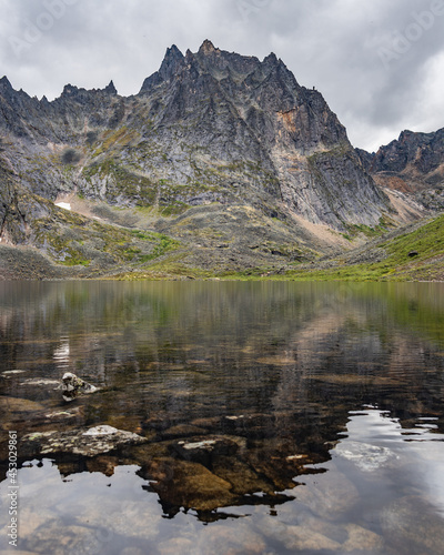 Stunning lake in Yukon  Canada during a cloudy summer day with reflection of mountain peaks in the calm Grizzly Lake below. 
