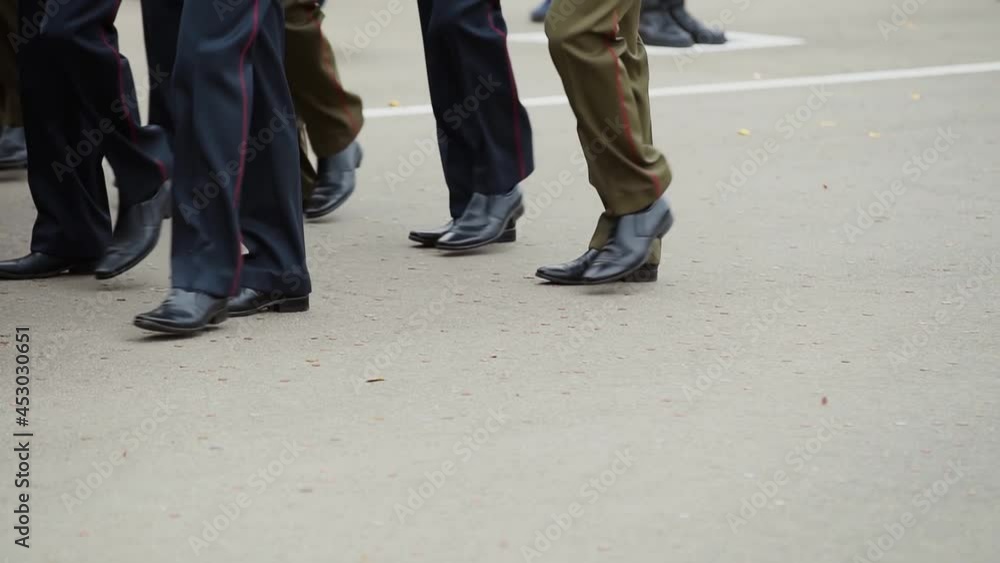 Military officers march in straight rows across tsquare and throw coins. Graduates celebrate graduation from Military Academy. Close-up of legs in green and blue pants with matching black shoes. Military officers march in straight rows across tsquare and throw coins. Graduates celebrate graduation from Military Academy. Close-up of legs in green and blue pants with matching black shoes.
