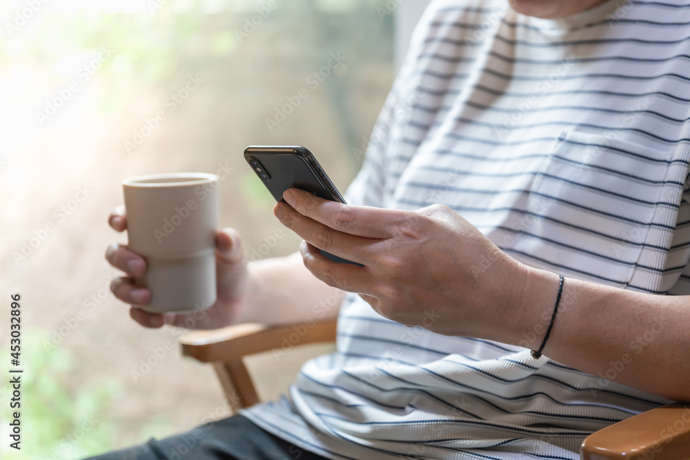Closeup of man hand using mobile smartphone and holding mug cup of hot coffee. Closeup of man hand using mobile smartphone and holding mug cup of hot coffee.