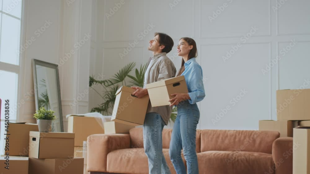 Moving day. Happy young couple in love coming to room with moving boxes and discussing new apartment Moving day. Happy young couple in love coming to room with moving boxes and discussing new apartment