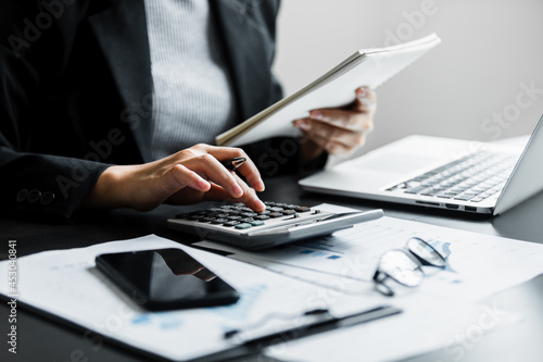 Close up of businesswomen or accountant using calculator calculate while working analytic business report on the workplace, Planning financial and accounting concept. photo