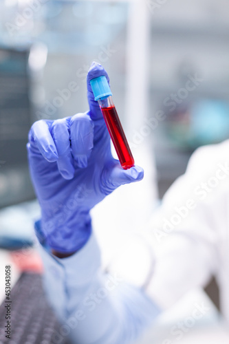 Scientist researcher woman holding blood vacutainer discovering disease infection working at medical biochemistry experiment. Chemist doctor discovering virus expertise in hospital laboratory