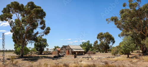 Panoramic view of a broken decaying old timber farmers workers home surrrounded by native trees on a dry barron agricultural property, rural Victoria, Australia photo