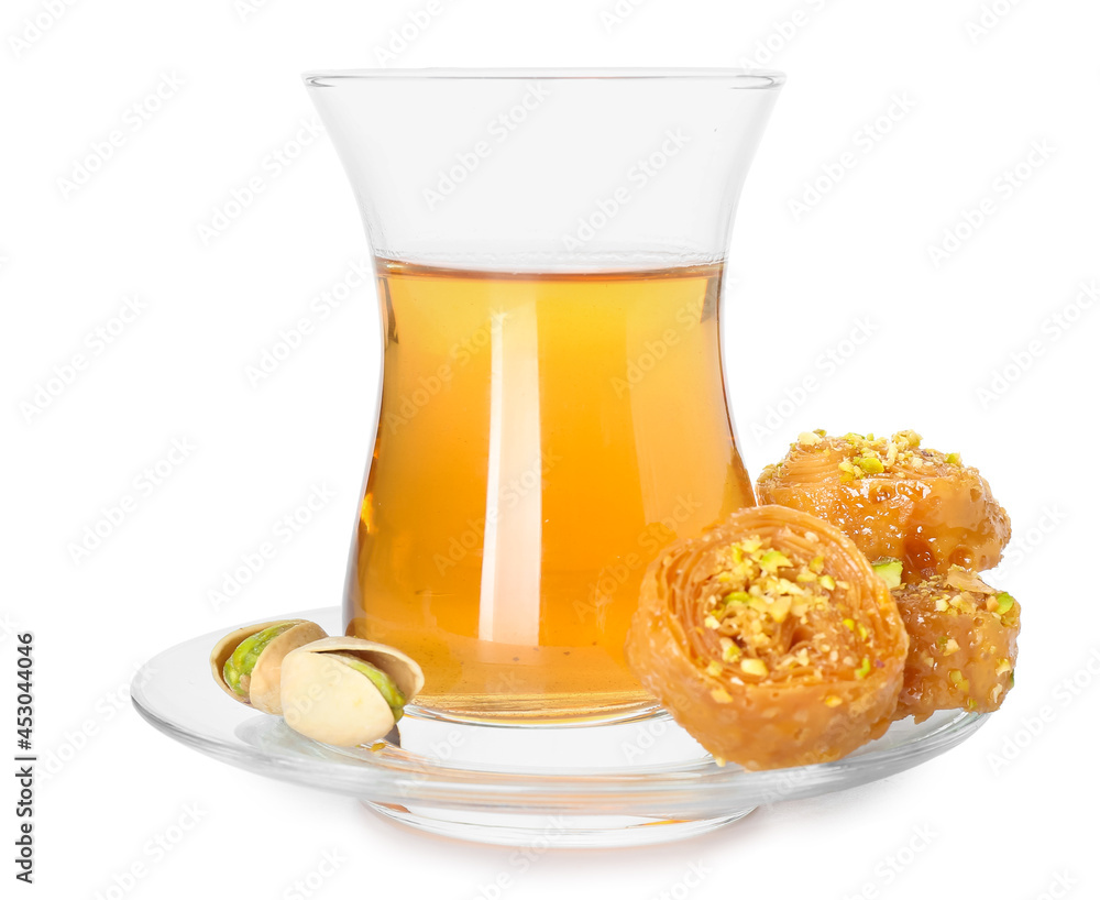Glass of tasty Turkish tea with delicious baklava on white background Glass of tasty Turkish tea with delicious baklava on white background