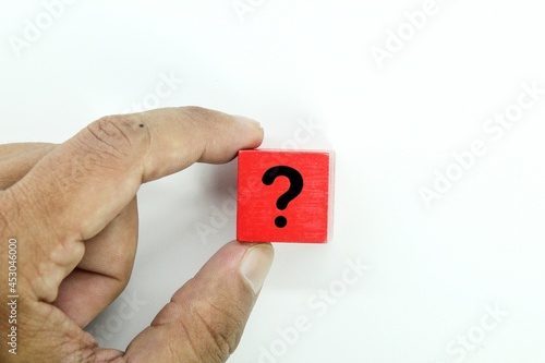 a hand holding a red cube with a question mark icon