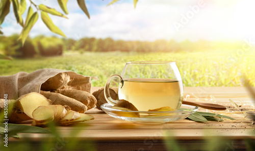 Organic ginger infusion and root on wooden table in nature photo