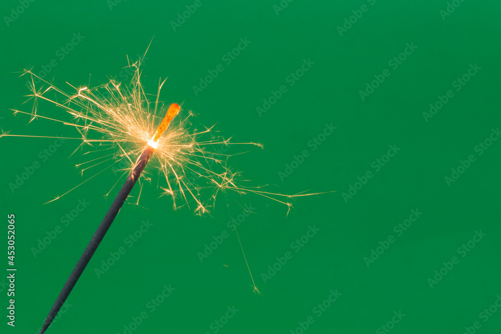 Fototapeta premium Burning firework sparkler on green background 