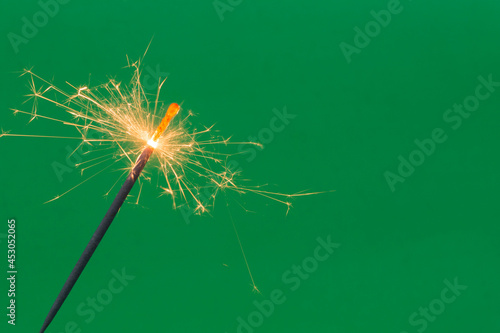 Fototapeta Naklejka Na Ścianę i Meble -  Burning firework sparkler on green background 