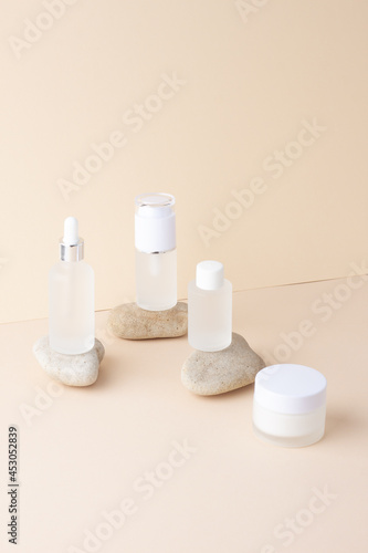 Cosmetic skin care products with stones on pastel beige background. Close up, copy space