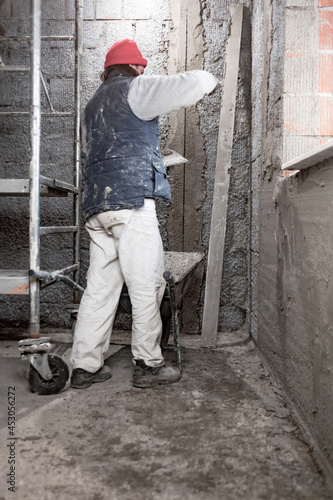 Real construction worker working on a wall inside the new house.