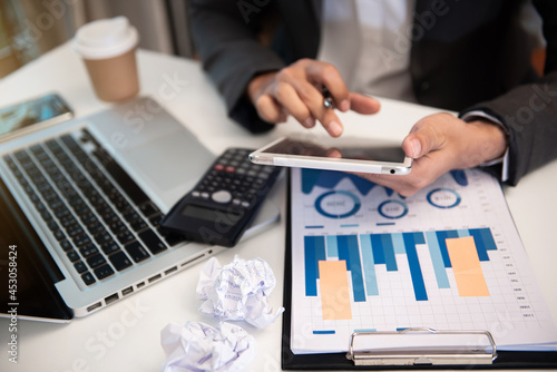 Business documents on office table with laptop and digital tablet and graph financial.