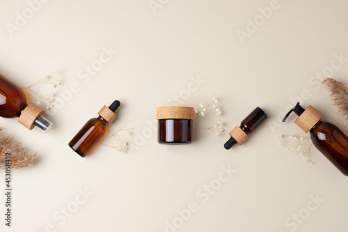 Cosmetic skin care products with flowers and pampas. on pastel beige background. Flat lay, copy space
