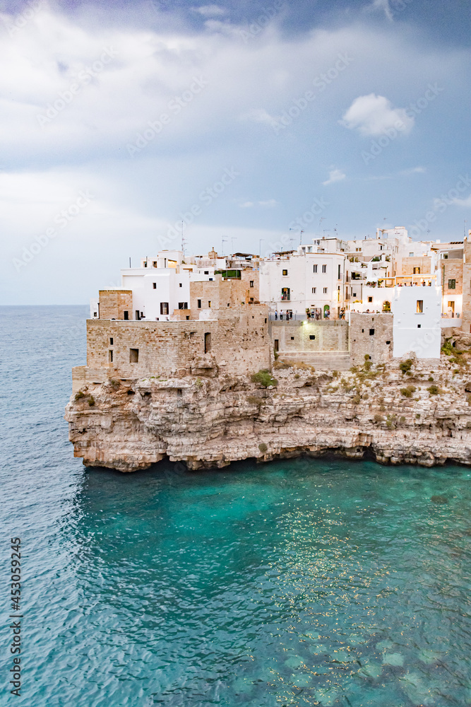 Polignano a Mare. Town on the cliffs, Puglia region, Italy, Europe. Traveling concept background with old traditional houses, dramatic sky, Mediterranean Sea, vertical