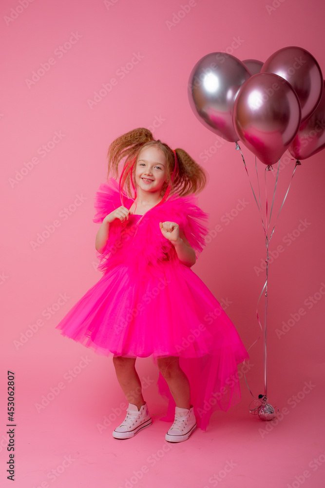 little girl on a pink background holding balloons, celebrating her birthday