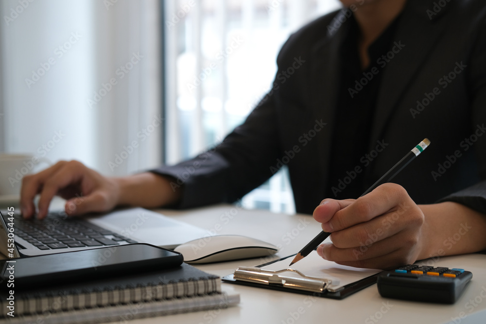 Closed up with man is working by using a laptop and writes on notes. Closed up with man is working by using a laptop and writes on notes.