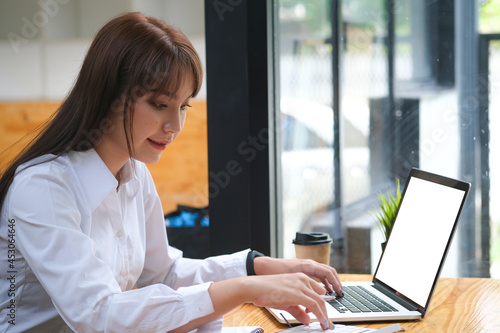 The businesswoman using a laptop and notepapers to working, blank screen of laptop.