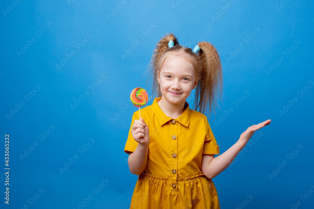 little girl holds a lollipop on a blue background little girl holds a lollipop on a blue background
