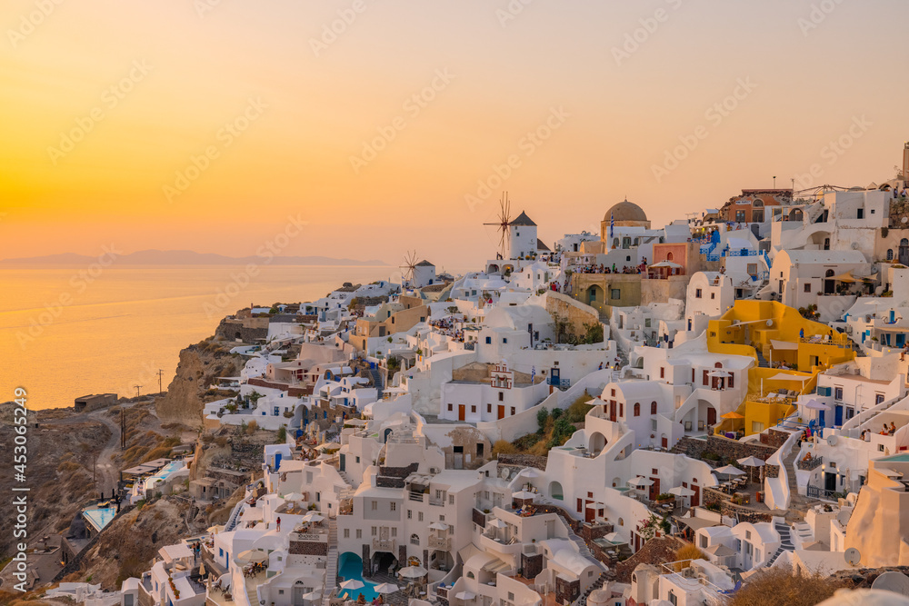 Sunset view of the cliff side white cave accommodation of Oia on the Greek island of Santorini