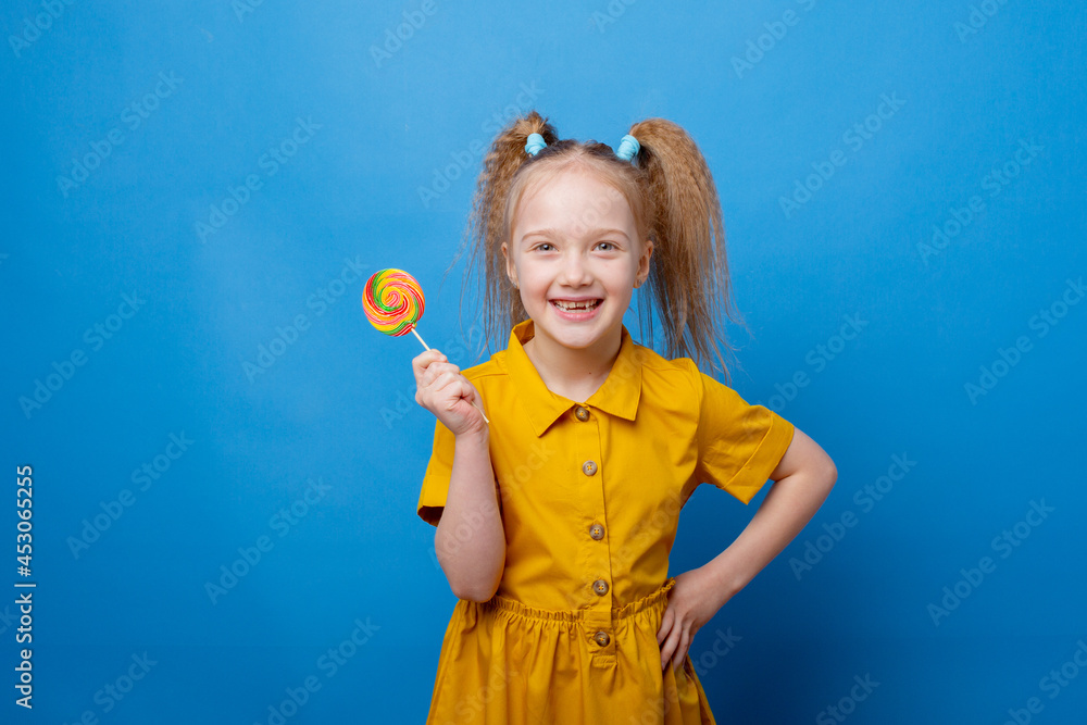 little girl holds a lollipop on a blue background little girl holds a lollipop on a blue background