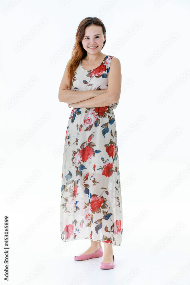 Isolated portrait studio shot of Asian happy young beautiful female model in white flowers pattern sleeveless long dress standing smiling look at camera crossed arms in front of white background Isolated portrait studio shot of Asian happy young beautiful female model in white flowers pattern sleeveless long dress standing smiling look at camera crossed arms in front of white background