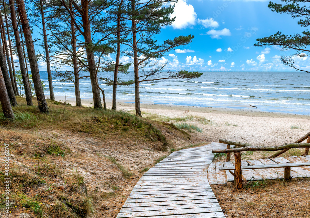 Wooden resting spot and footpath leading to sandy beach of the Baltic Sea