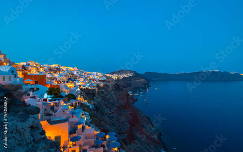 Night time blue hour view of the cliff side white cave accommodation of Oia on the Greek island of Santorini. 