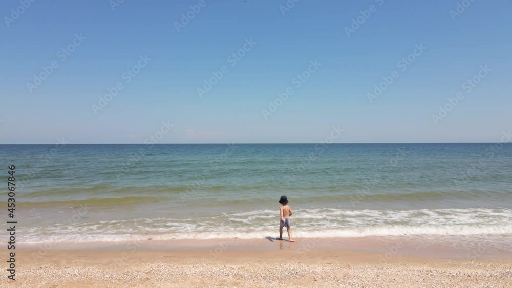 four year old boy in striped swimming trunks and a panama hat is playing four year old boy in striped swimming trunks and a panama hat is playing