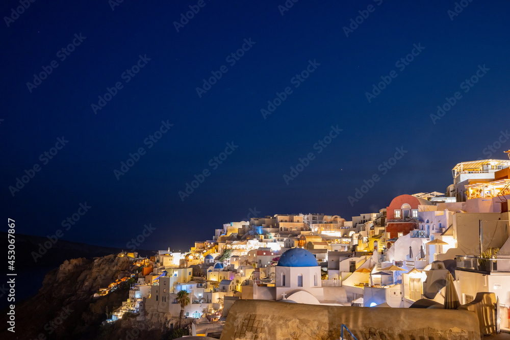 Night time blue hour view of the cliff side white cave accommodation of Oia on the Greek island of Santorini.  
