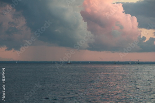 Clouds at sunset, the sea and sailboats